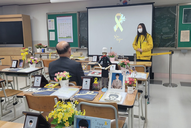 위원장 세월호 학생의 위패들이 있는 책상에 직접 앉아 발표를 화면과 함께 보는 장면